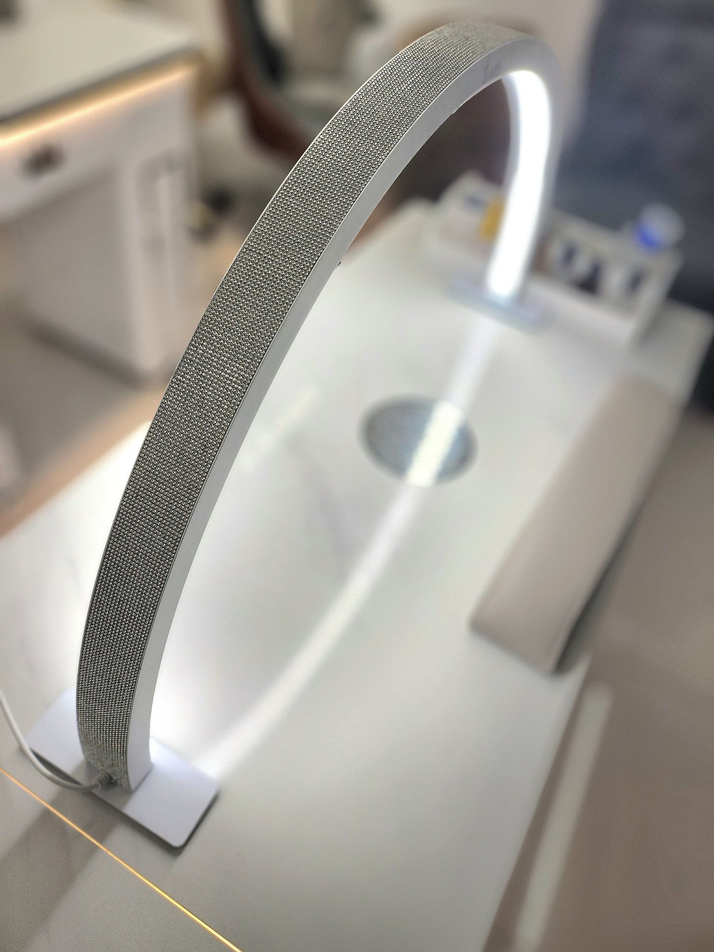 A half-moon shaped desk lamp with a glittery texture, emitting light from its curved surface.
