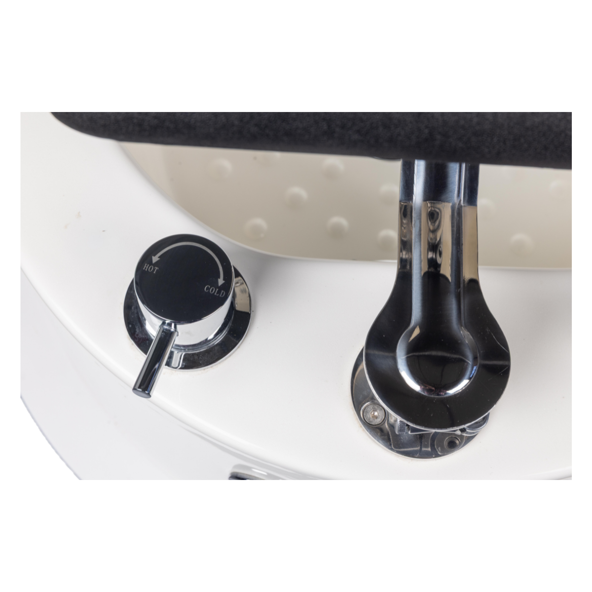 Chrome faucet and control knobs on a white sink with a black handle.