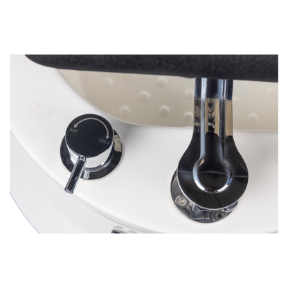 Chrome faucet and control knobs on a white sink with a black handle.