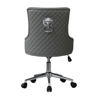 Rear view of a grey upholstered swivel office chair with diamond quilting, silver lion head ring pull detail on the backrest, studded nailhead trim around the edges, and a chrome five-star base with castors and height adjustment lever.