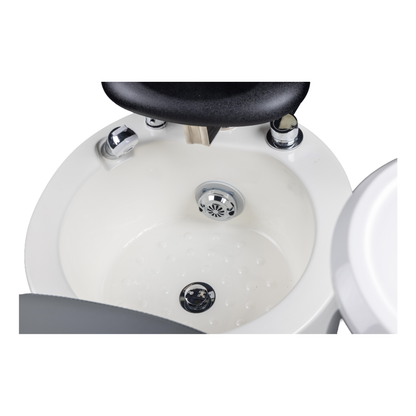 Close-up of a white salon sink of a pedicure chair with black faucet and drain cover on a white background