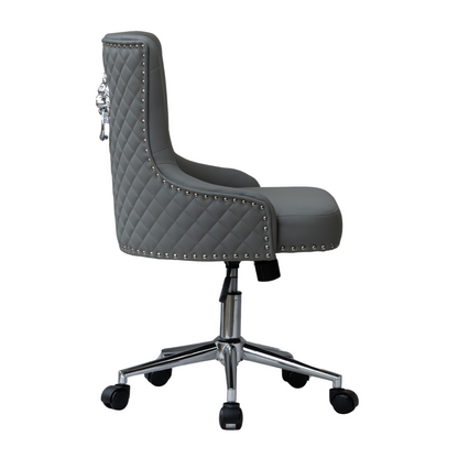 Side view of a grey upholstered swivel office chair with diamond-quilted backrest, silver lion head ring pull detail, studded nailhead trim along the edges, padded seat and armrest curve, and a chrome five-star base with castors and height adjustment lever.